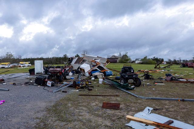 Debris litters weather-damaged properties at the intersection of County Road 24 and 37 in Clanton, Ala.